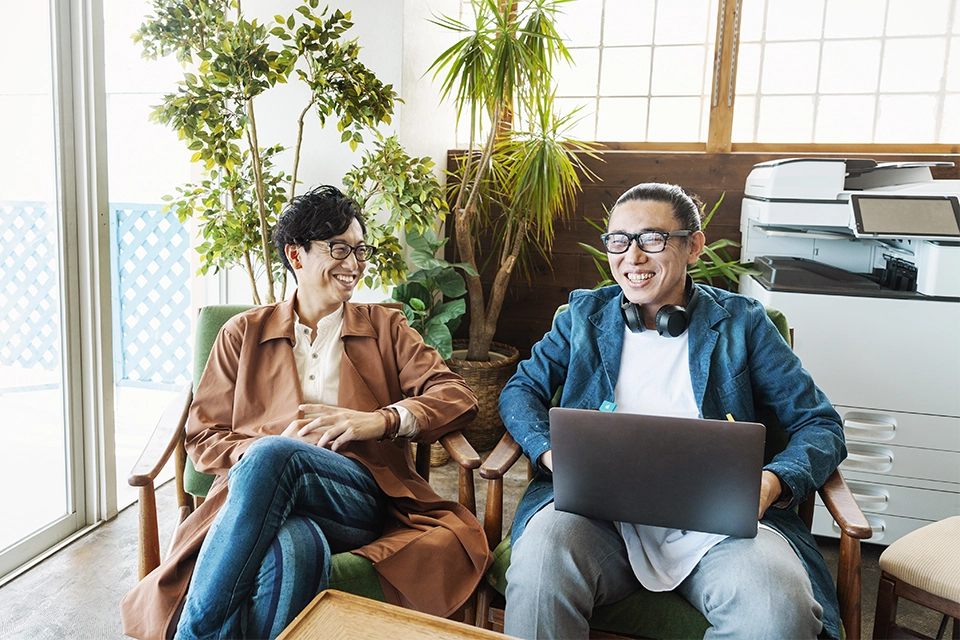 Two smiling people in an office discussing the benefits of marketing automation with one holding a laptop
