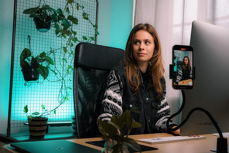 A potential ideal influencer recording a video at a desk with plants in the background
